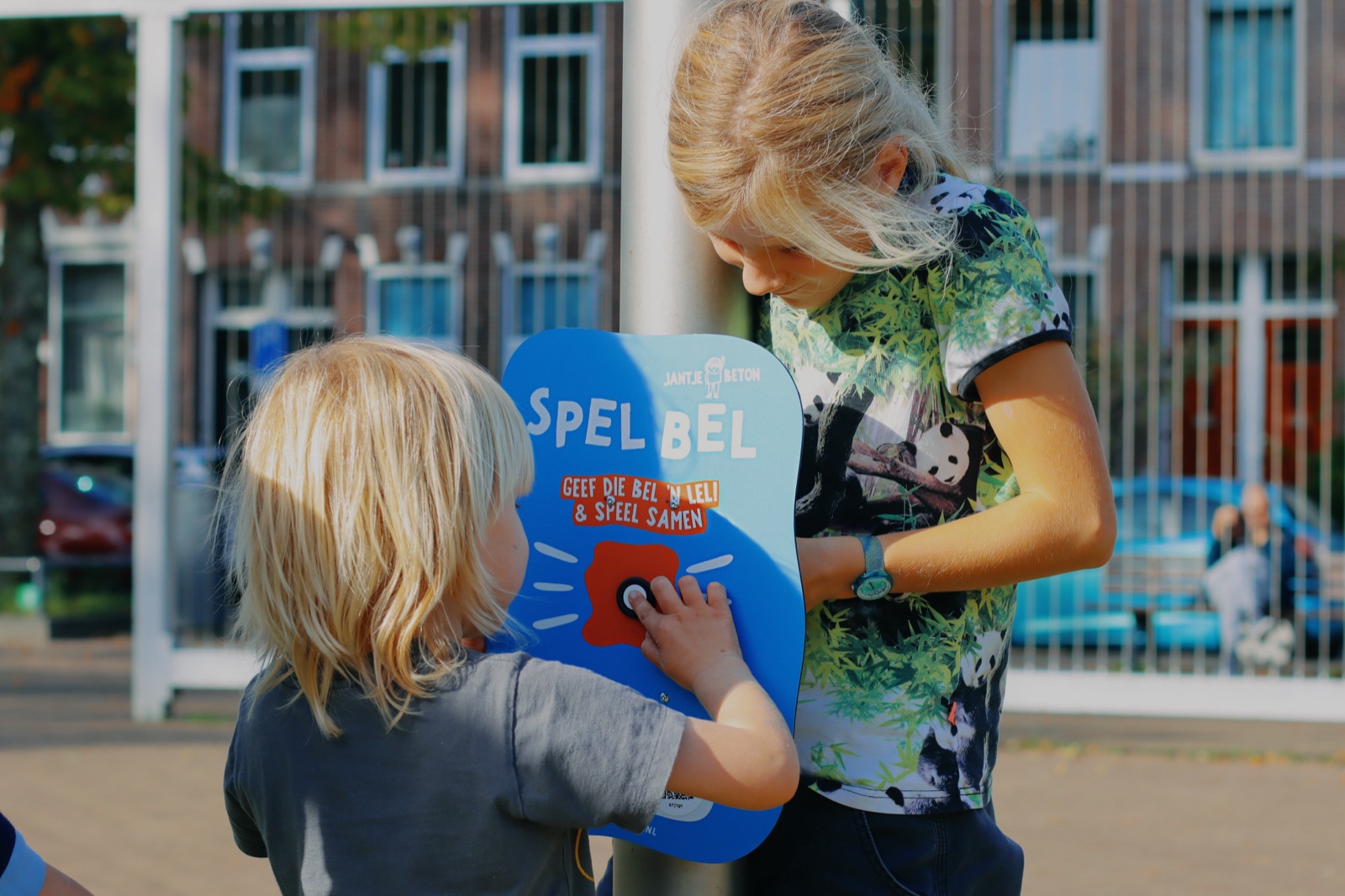 Twee kinderen drukken op de knop van een SpelBel in de speeltuin